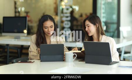 Porträts von zwei Geschäftsfrauen, die bei Meetings mit Tablets zusammenarbeiten Tabelle Stockfoto