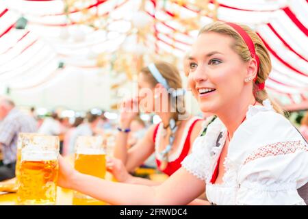 Frauen trinken bayerisches Bier im Zelt auf dem Oktoberfest oder Dult Dirndl tragen Stockfoto