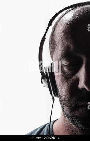 Fröhlich attraktive junge Mann im Kopfhörer hören von Musik über weißem Hintergrund Stockfoto