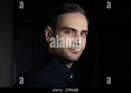 Ein Influencer, Künstler und Musiker, Kleid mit schwarzem Hemd, posiert für die Kamera in einem seiner fotografischen Shootings für soziale Netzwerke, in einem dunklen b Stockfoto