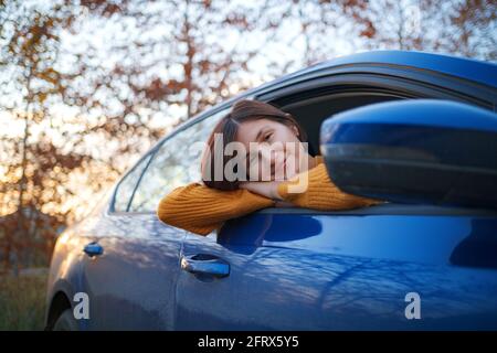 Fröhliche asiatische Frau in einem Auto bei Sonnenuntergang. Die Idee und das Konzept der Reise, Entdeckung und Erholung Urlaub Stockfoto