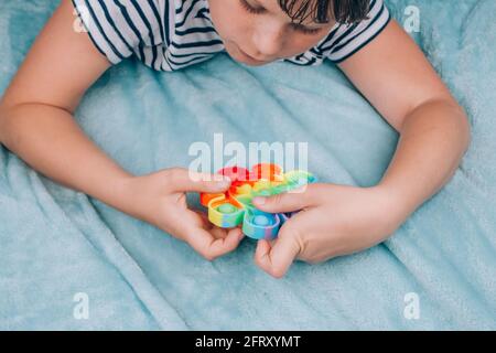 Junge spielt mit Regenbogen Pop es fidget Spielzeug. Push Bubble Fidget Sinnesspielzeug - waschbares und wiederverwendbares Stressabbau-Spielzeug. Antistress Spielzeug für Kinder mit Stockfoto
