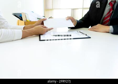 Junge Arbeiter fühlen sich schlecht und traurig, er erhalten Rücktritt Nachricht von seinem Chef und Unternehmen. Trauriger Geschäftsmann packt seine Zugehörigkeit in die Box und geht nach Hause. Stockfoto