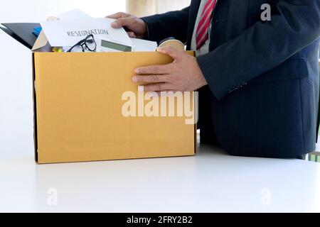 Arbeiter fühlen sich schlecht und traurig, er erhalten Rücktritt Nachricht von seinem Chef und Unternehmen. Trauriger Geschäftsmann packt seine Zugehörigkeit in die Box und geht nach Hause. Stockfoto