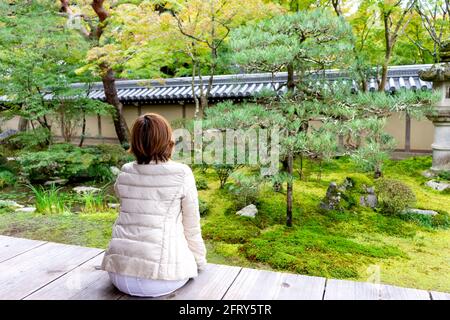 Asiatische Frau sitzen und Blick auf Japan Garten zu entspannen Im Naturpark in der Stadt Kyoto Stockfoto