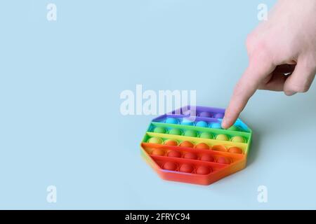 Trendy beliebtes Silikon bunte Anti Stress Pop it Spielzeug in Hexagon-Form. Nahaufnahme. Jemand schiebt Sinneseindrücke. Trendiges Hype-Thema von tik tok. Stockfoto