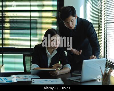 Porträts von Geschäftsleuten, die mit einem Laptop und Papierkram zusammenarbeiten Tagungsraum Stockfoto