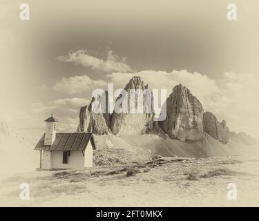 Italien. Das Bild zeigt die Kletterkapelle auf der drei Zinnen Hütte [Rifugio Locatelli], die auf die berühmten drei Türme blickt, die auf Deutsch drei Zinnen heißen, aber auf Italienisch poetischer Weise als die drei Zinnen di Laverado in der östlichen Region der italienischen Dolomiten in Sexten-Sexten genannt werden. Während des Ersten Weltkriegs, bekannt als der Weiße Krieg, stellten die Gipfel eine natürliche Barriere zwischen den Italienern und den streikenden Österreichern dar, wobei die Front durch die Gipfel lief. Stockfoto