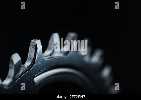 Sternenzähnchen-Muster mit Fahrradketten-Mechanismen auf schwarzem Hintergrund. Dark Key, Draufsicht Black Star Pleuelsystem für schmale breite Fahrräder. Stockfoto