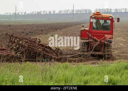 Ein alter roter Raupentraktor arbeitet auf dem Feld. Agrarkonzept Stockfoto