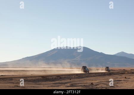 Zwei Geländewagen mit Geländewagen im Geländewagen fahren auf einer Touristensafari über Land durch die Wüstenlandschaft Boliviens. Stockfoto