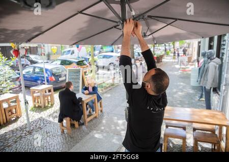 Potsdam, Deutschland. Mai 2021. Ouni Ben, Kellner, öffnet einen Sonnenschirm vor einem vietnamesischen Restaurant in Potsdam. Quelle: Christoph Soeder/dpa/Alamy Live News Stockfoto