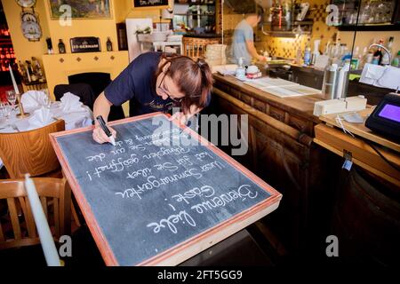 Potsdam, Deutschland. Mai 2021. Romy Wismer, eine Kellnerin, schreibt auf einer Tafel in einem französischen Restaurant in Potsdam. Quelle: Christoph Soeder/dpa/Alamy Live News Stockfoto