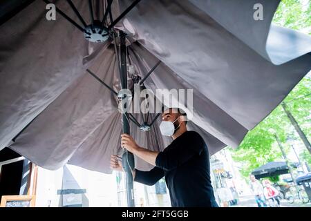 Potsdam, Deutschland. Mai 2021. Ouni Ben, Kellner, öffnet einen Sonnenschirm vor einem vietnamesischen Restaurant in Potsdam. Quelle: Christoph Soeder/dpa/Alamy Live News Stockfoto