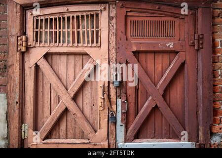 Alte Scheunentüren, mit abblätternder Farbe, mit zwei großen Metallschlössern darauf. Muster Stockfoto