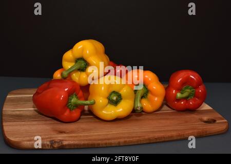 Gemischte Paprika auf einem hölzernen Schneidebrett mit Schwarz Hintergrund Stockfoto