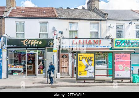 Typische Straße mit kleinen unabhängigen Einzelhandelsgeschäften in London East End A Coffee Shop und Asian Jewelry’s, Newham, London Stockfoto