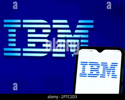 In dieser Abbildung ist ein Logo der IBM (International Business Machines) Corporation zu sehen, das auf einem Smartphone und im Hintergrund zu sehen ist. Stockfoto