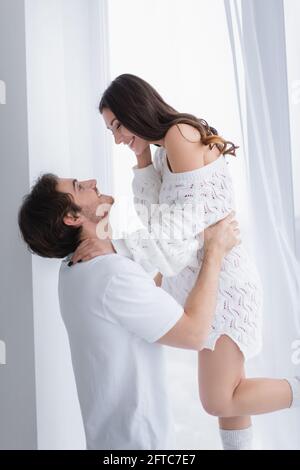 Seitenansicht eines jungen Paares, das sich gegenseitig anlächelt Zu Hause Stockfoto
