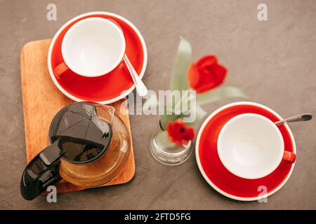 Flach liegend, Teekannen mit Tee und zwei rote leere Tassen auf Holztisch. Stockfoto