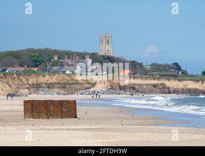 Ein Blick auf Happisburgh Sandstrand mit Menschen zu Fuß und Ein Blick auf die Kirche von Happisburgh im Hintergrund Stockfoto