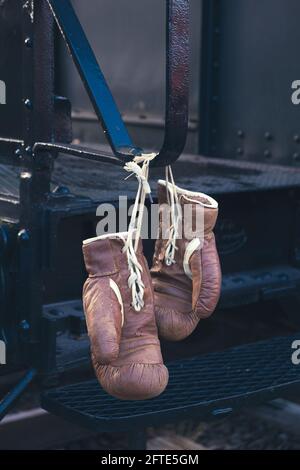 Zwei braune Boxhandschuhe hängen aus Stahlgriff Stockfoto