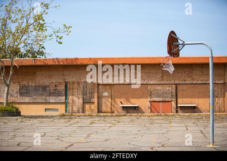 Ein veraltetautes Gebäude und ein verlassene alte Basketballplatz Stockfoto