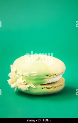 Grüner Kuchen Makaron oder Makaron auf grünem Hintergrund. Bunte Mandelkekse. Französischer Makkaronenkuchen aus nächster Nähe. Makronen auf farbigem Hintergrund Stockfoto