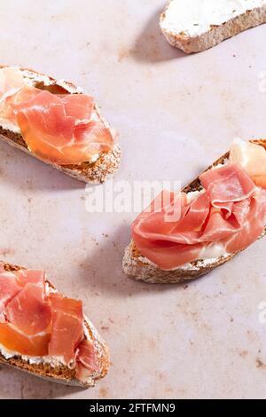 Scheiben frisches Baguette mit Schlagsahne und Serrano-Schinken gekrönt. Stockfoto