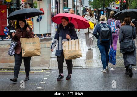 London, Großbritannien. Mai 2021. Menschen, die im Regen in der Oxford Street einkaufen. Das Office for National Statistics (ONS) hat berichtet, dass die Einzelhandelsumsätze im April um 10 % über dem Stand vor der Pandemie lagen, wobei der Absatz von Kleidung im Vergleich zum März um 70 % gestiegen ist. Es wurde vermutet, dass der Anstieg ein Beleg für die aufgestaute Nachfrage ist, da am 12. April in England wieder Geschäfte eröffnet wurden, die nicht unbedingt notwendig sind. Kredit: Stephen Chung/Alamy Live Nachrichten Stockfoto