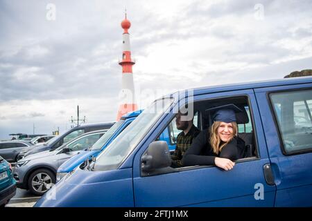 Bremerhaven, Deutschland. Mai 2021. Absolventin Rieke Helmers schaut aus ihrem Auto, während Absolventen der Hochschule Bremerhaven an Autos bei einer Abschiedszeremonie und der Zertifikatsübergabe am Willy-Brandt-Platz teilnehmen. Die Teilnehmer konnten die Zeremonie vom Auto aus auf einer Bühne und über einen Bildschirm verfolgen. Quelle: Sina Schuldt/dpa/Alamy Live News Stockfoto