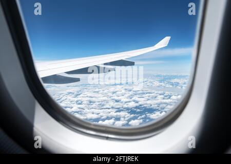 Blick auf Wolken und Flügel aus einem Flugzeugfenster Stockfoto