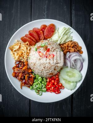 Ein Gericht aus thailändischem, gebratenen Reis mit Garnelenpaste Schwarzer Holzhintergrund Stockfoto