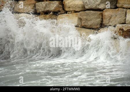 Wellenbruch an der Steinmauer Stockfoto