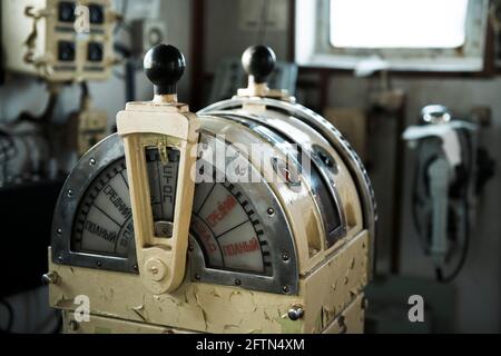 Navigationsbrücke auf verlassenen Schiff. Altes, verderbtes Schiffsradhaus. Steuergerät des Schiffs. Russische Worte: Vorwärts/achteraus, voll, halb, langsam, tot langsam Stockfoto