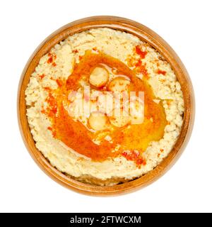 Hummus Dip mit Paprikapulver und Öl, in einer Holzschale. Nahost-Dip, Aufstrich oder herzhaftes Gericht aus gekochten, pürierten Kichererbsen. Stockfoto
