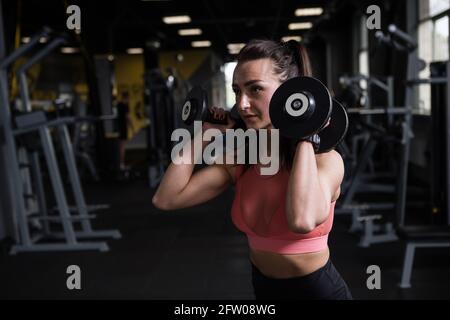 Fitness-Frau beim Training mit Kurzhanteln im Fitness-Studio, Copy Space Stockfoto