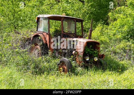 Alte rostige vintage verlassenen Traktor auf einem Feld mit hohem Gras bewachsen. Stockfoto