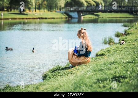 Zwei bezaubernde Schwestern füttern Enten an einem Fluss im Sommer Stockfoto