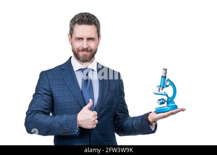 Mann im Anzug präsentiert moderne Mikroskop isoliert auf weißem zeigen Daumen nach oben, Wissenschaft und Wirtschaft. Stockfoto