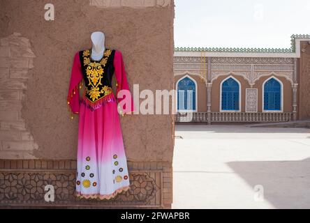 Ein traditionelles und festliches Kleid, das an einer Wand hängt Kashgar, Xinkiang, Volksrepublik China, 2019 Stockfoto