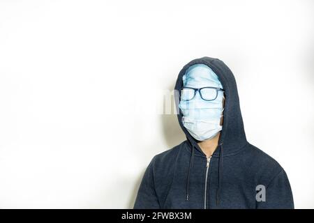 Porträt eines Mannes mit maskierten Gesichtes Und eine Brille über ihnen mit einer blauen Jacke mit Kapuze Auf weißem Hintergrund Stockfoto