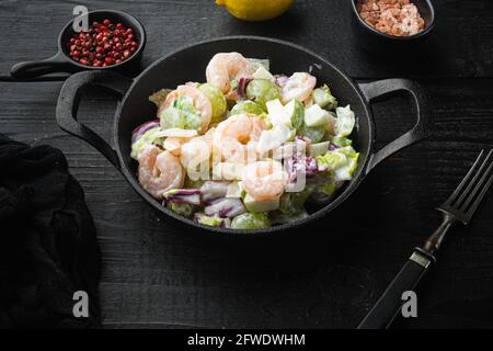 Salat mit Garnelen, Avocado, Tomaten und Mayonnaise auf dem Salat-Set, mit Sauce Apfel und Traube, auf schwarzem Holztisch Stockfoto