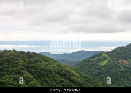 Eine wunderschöne Berglandschaft mit waldreichen Gipfeln und wolkenbedecktem Himmel. Stockfoto