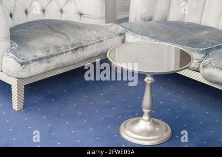 Stilvolles Interieur des Zimmers mit bequemen grauen Polstermöbeln und einem silbernen Couchtisch. Stockfoto