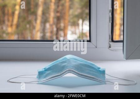Öffnen Sie das Plastikfenster mit einer Schutzmaske auf dem Hintergrund des Waldes Stockfoto