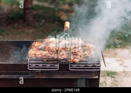 Kochen marinierte Hähnchenschenkel in Sauce und Gewürze auf einem Grill. Saftige Fleischstücke, mariniert mit Rauch aus Holzkohle. Gebraten Stockfoto