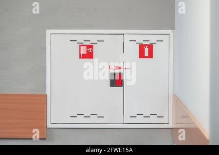 Feuerlöscherschrank. Feuerlöscherschrank auf grauem Wandhintergrund im Bürogebäude, Arbeitsschutzkonzept. Stockfoto