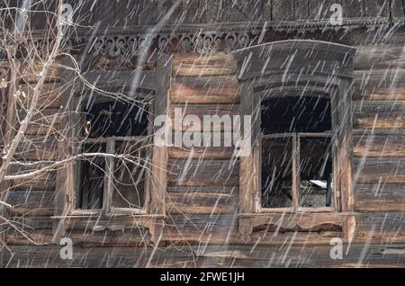 Fragment einer Fassade aus Rundholz mit verkohlten Fenstern. Stockfoto