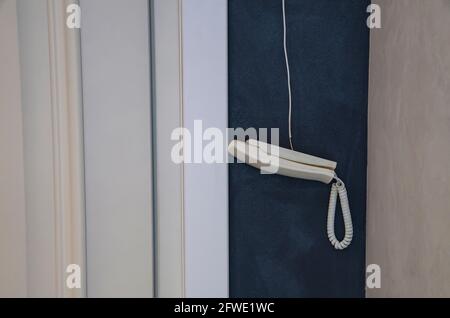 Vintage-Telefonhörer, der auf einem Kabel auf einem hellen Hintergrund mit Kopierfläche hängt. Stockfoto